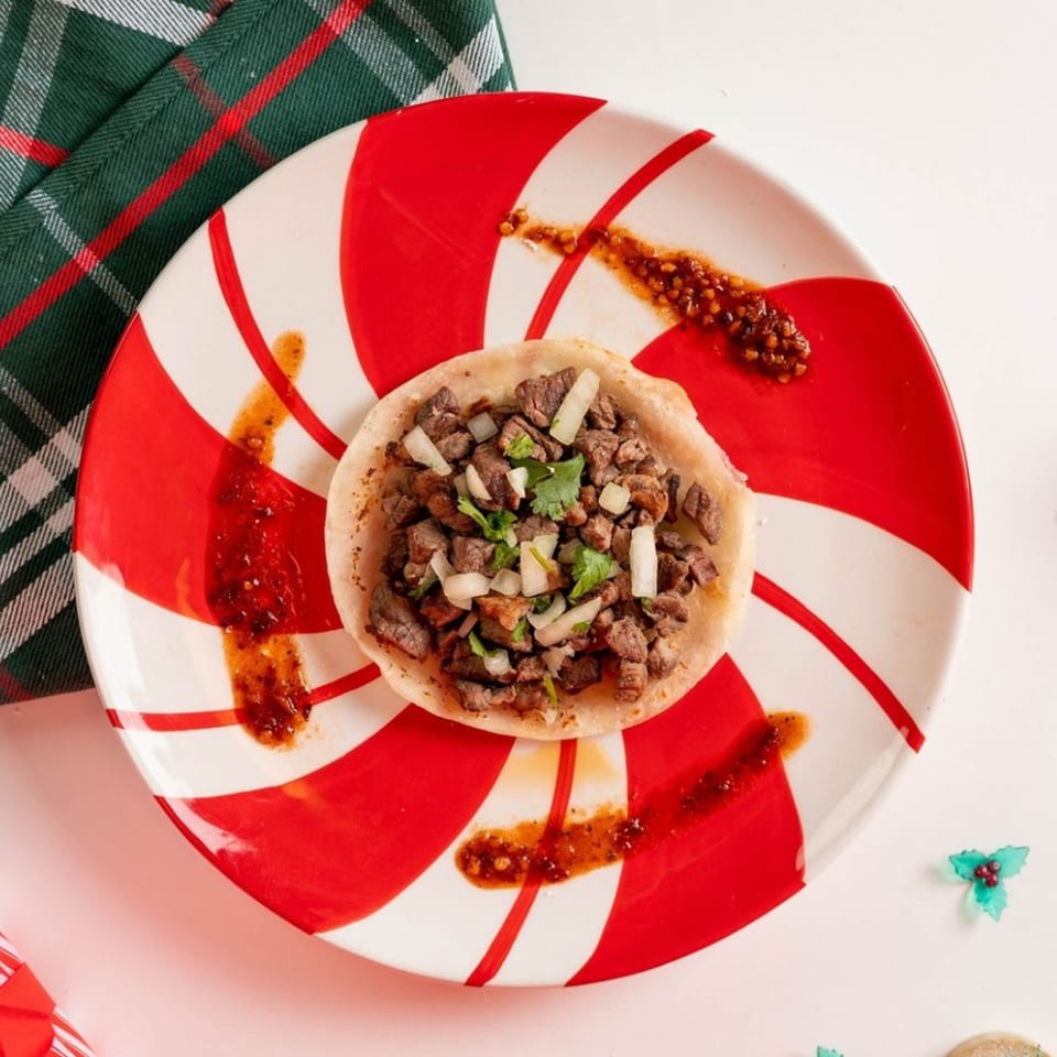 A Santa Madre Taco Shop carne asada taco with onions and cilantro on a candy cane plate.